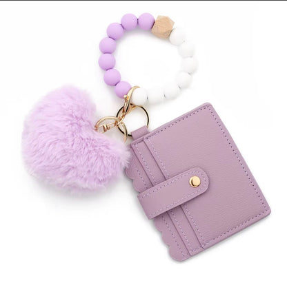 Lavender wallet with keychain featuring pom-pom and beads on a white background